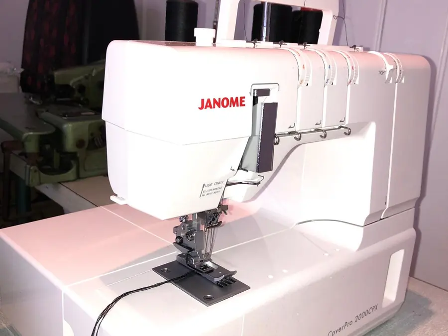 Workbench with a threaded overlocker, fabric and bags stacked behind